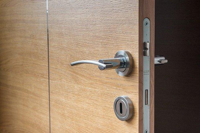 Close-up of a wooden door with a modern silver handle and a keyhole in natural light