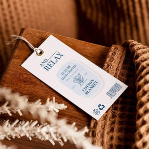 Luxury hand-crafted cotton blanket with a fabric tag on wooden surface and warm brown knitted texture