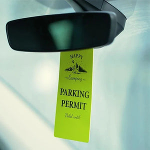 Bright green car mirror hanger with Happy Camping parking permit and tent design inside vehicle