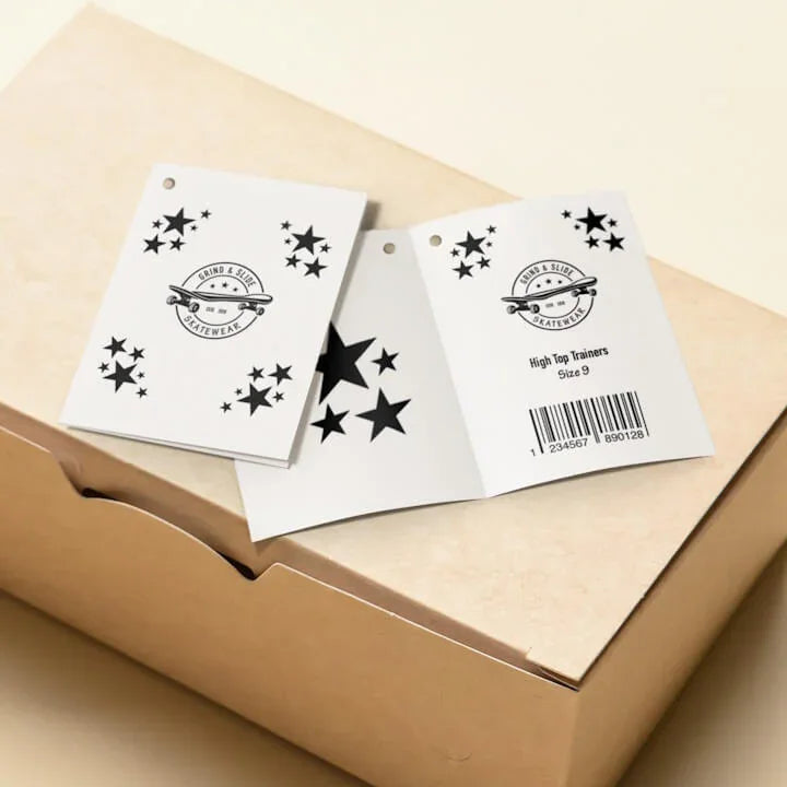 Folded white product tags with black star designs and skateboard logo on a cardboard box